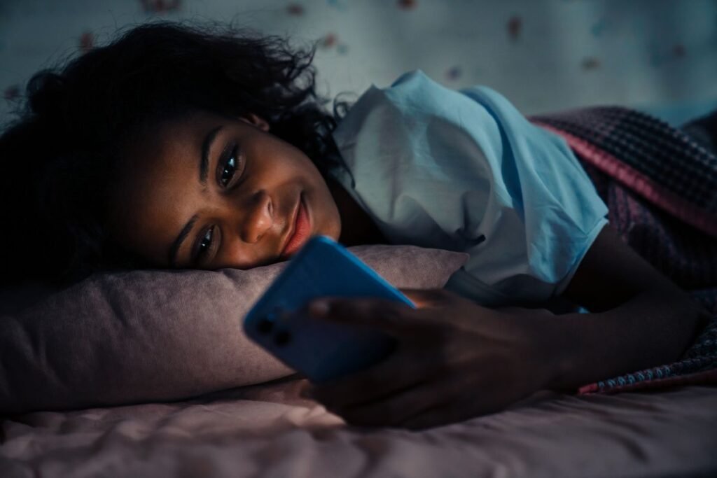 A teen girl using a phone before sleep.